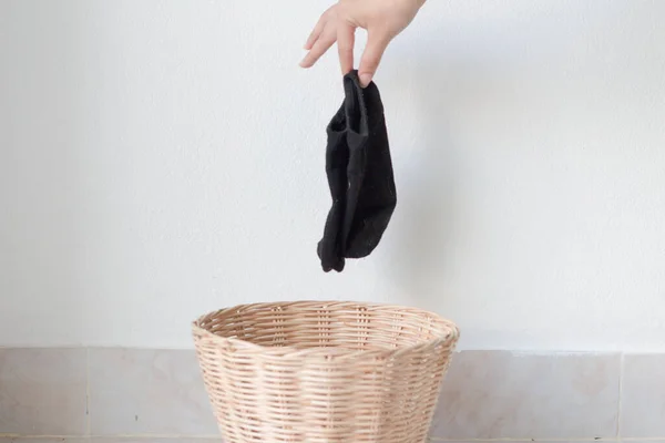 Woman putting dirty socks in a laundry basket.copy space.