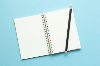 Mavi pastel arka plan üzerine boş bir defter. En az stil.