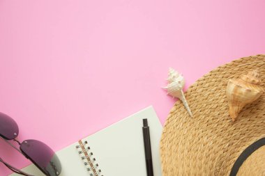 Plaj aksesuarları hasır şapka güneş gözlüğü, not defteri, pastel arka planda deniz kabuğu yaz tatili ve tatil konsepti..