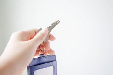 Beyaz duvar arka planında ev anahtarı ve anahtar kartı tutan kadın..