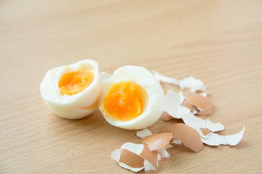 Half of boiled egg and peeled on wooden table background.