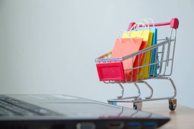 Tramvayda renkli kağıt alışveriş torbaları ya da dizüstü bilgisayarlı hoplama arabası, E-ticaret konsepti.