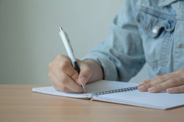 Not defterine kalem yazan bir kadın el..