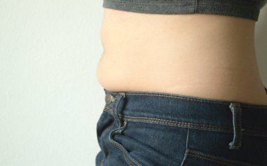 Kot giyen şişman bir kadın. Elleri kalçasında kilo aldığı için pantolonu kapatamıyor. Diyet konsepti.