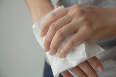 Beyaz arka planda ellerini kağıt mendille temizleyen bir kadın. Sağlık hizmetleri kavramı.