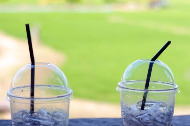 Yeşil arka planda plastik bardakta buz.