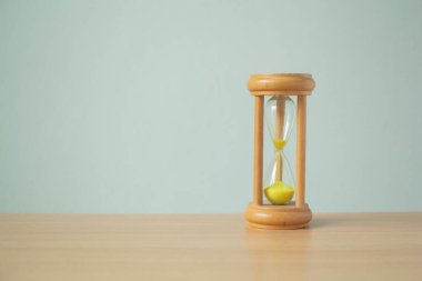 Kum saati ampulleri arasında koşan sarı kum beyaz arka planda fotokopi masasının üzerinde solukluk halinde geri sayım süresi minimumda..