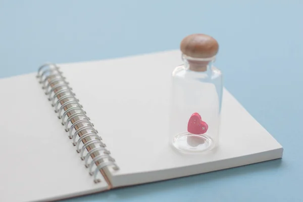 Mini Corazón Rosa Botella Sobre Papel Cuaderno Sobre Fondo Azul — Foto de Stock