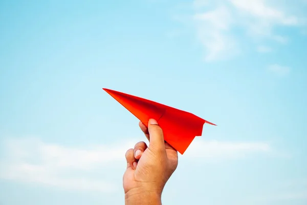 Man hand holding paper airplane on blue sky background new innovation, creativity and freedom concept.