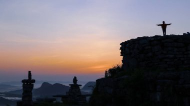 Yogadaki adamın silueti dağın tepesinde duruyor. Dushan County, Guizhou, Çin 'deki karst zirvesinin tepesinde.