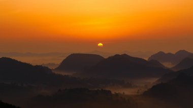 Yogadaki adamın silueti dağın tepesinde duruyor. Dushan County, Guizhou, Çin 'deki karst zirvesinin tepesinde.