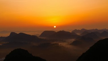 Yogadaki adamın silueti dağın tepesinde duruyor. Dushan County, Guizhou, Çin 'deki karst zirvesinin tepesinde.