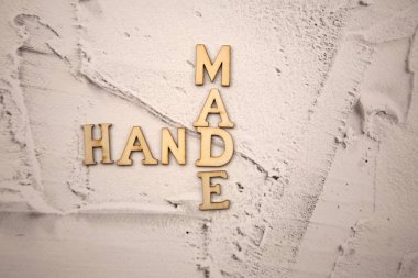 El kelimesi ahşap harflerden yapılmış. Beton bir duvarda beyaz alçı var.