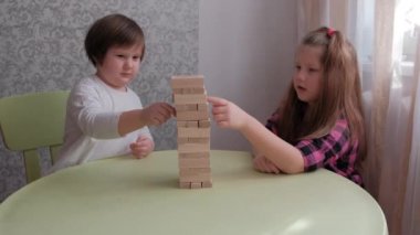 Çocuklar Jenga oynar ve evde kalır, çocuklar eğlenceli ve eğlencelidir, ailedeki çocuklar, mutlu erkek çocukları kapar yaşlı kız çocuk odun blokları oyunu, neşeli 
