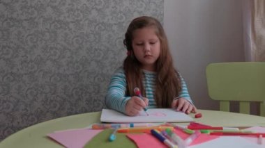 Çocuk bir kartpostal yapıyor bir kağıt parçasına kalp çiziyor ve aşk kelimesini yazıyor. Sevgililer günü için kartpostal, anneler günü, babalar günü. Çocukların yaratıcılığı