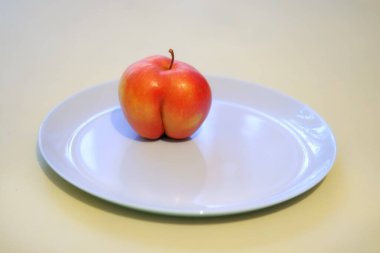 Ugly apple like ass on a blu plate, great design for any purposes. Fresh fruit. Food background. Sweet fruit. Sweet food. ass-like apple