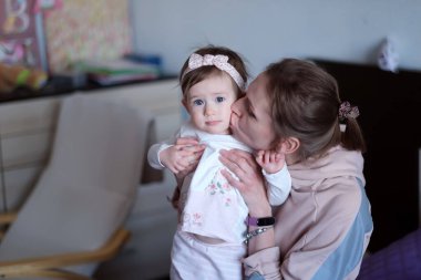 Anne, bebeğin sevgilisine sarılıp öpüyor. Kız kameraya bakıyor. Aile hayatı.