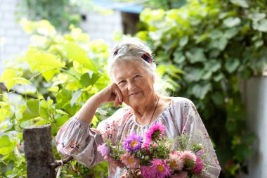 Güneşli bir yaz gününde bahçede çalışırken emekliliğinin tadını çıkaran, aktif bir yaşam tarzı olan sarışın yaşlı bir kadının portresi.