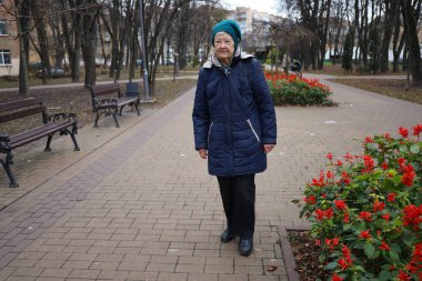 Yaşlı bir bayan bir sonbahar günü parkta yürür, doğanın tadını çıkarır, telefonda konuşur.