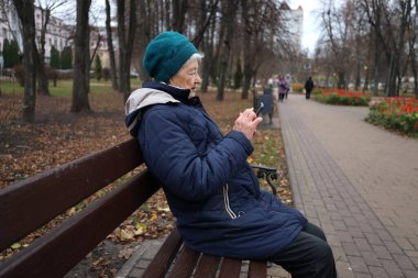 Yaşlı bir bayan bir sonbahar günü parkta yürür, doğanın tadını çıkarır, telefonda konuşur.
