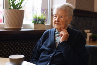 Restoranda yemek yiyen 90 yaşında, kır saçlı, son sınıf öğrencisi bir kadının portresi. Çorba, ana yemek, çay. Konuşma.