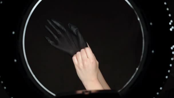 Mujer con guantes de látex negro en un salón de belleza con hermosa iluminación circular. Preparación del procedimiento en el salón — Vídeos de Stock