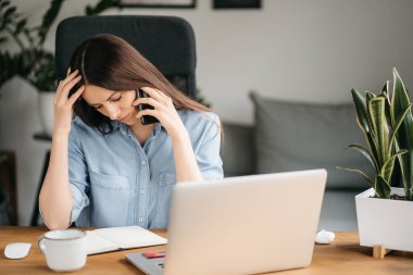 Genç, güzel bir kadın video odasında konuşuyor ve ana ofiste masada otururken el sallıyor.