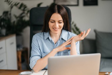 Evde bilgisayarla çalışan mutlu ve serbest bir genç kadın. Çevrimiçi öğrenim gören çekici iş kadını, dizüstü bilgisayar, web sörfü bilgileri veya internet mağazasından alışveriş yapıyor..