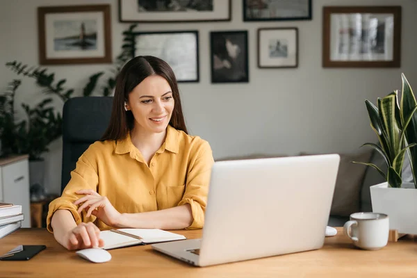 Strzał w głowę przyjemna młoda kobieta freelancer pracuje na komputerze w domu. Atrakcyjna bizneswoman studiuje online, za pomocą oprogramowania laptopa, informacji surfingu internetowego lub zakupy w sklepie internetowym. — Zdjęcie stockowe