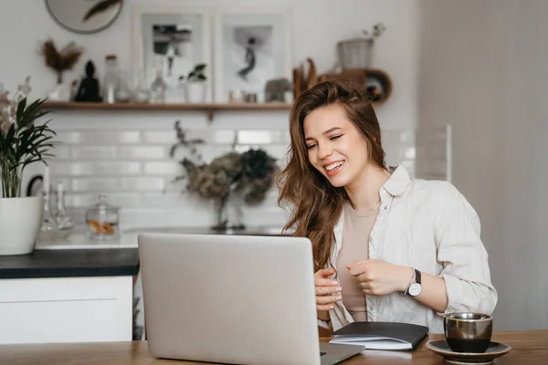 Mujer sonriente trabajando con computadora portátil bebiendo café, trabajando en casa, educación remota — Foto de Stock