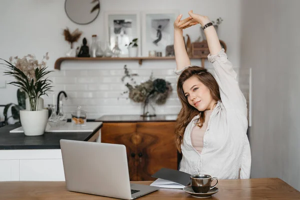 Jonge blonde vrouw stretching armen omhoog zitten in de voorkant van laptop — Stockfoto