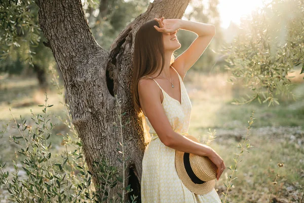 Portrait de belle jeune femme brune en chapeau de paille au coucher du soleil dans un jardin d'oliviers. Voyage en Italie, vacances d'été — Photo