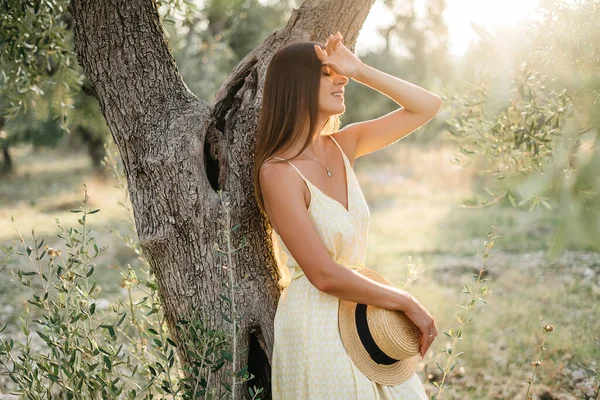 Een teder portret van een mooie brunette in mooi zonlicht. Vrouw in gele zomer linnen jurk in olijfboomgaard tuin. Natuurschoon.Reis naar Italië, zomervakantie — Stockfoto