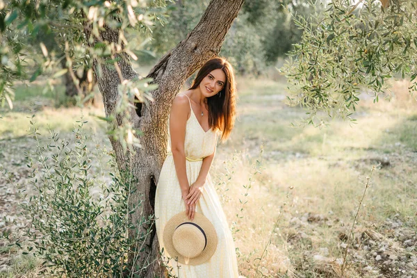 Tenero ritratto di bella donna bruna alla bella luce del sole. Donna in lino giallo estivo vestito in giardino di ulivi. Bellezza naturale.Viaggio in Italia, vacanze estive — Foto Stock