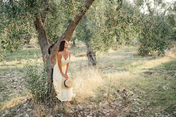 Tenero ritratto di bella donna bruna alla bella luce del sole. Donna in lino giallo estivo vestito in giardino di ulivi. Bellezza naturale.Viaggio in Italia, vacanze estive — Foto Stock