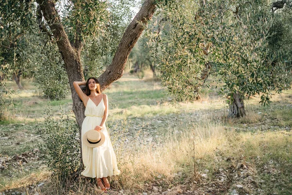 Tenero ritratto di bella donna bruna alla bella luce del sole. Donna in lino giallo estivo vestito in giardino di ulivi. Bellezza naturale.Viaggio in Italia, vacanze estive — Foto Stock