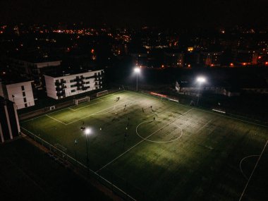 Aerial view of football pitch at night with amateur football players playing the game in the city clipart