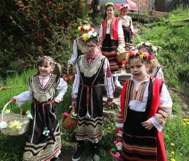 Gara Bov, Bulgarya- 24 Nisan 2021: Kızlar saçlarını renkli ve zengin bir şekilde süslüyor ve köyde dolaşıp şarkılar söyleyip dans ediyorlar, bu şekilde evlenmeye hazır olduklarını gösteriyorlar.