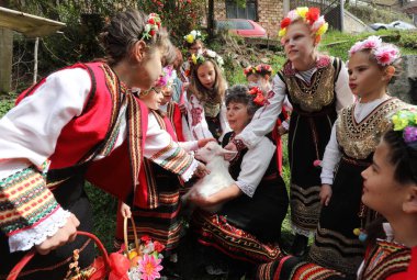 Gara Bov, Bulgarya- 24 Nisan 2021: Kızlar saçlarını renkli ve zengin bir şekilde süslüyor ve köyde dolaşıp şarkılar söyleyip dans ediyorlar, bu şekilde evlenmeye hazır olduklarını gösteriyorlar.