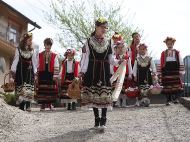 Gara Bov, Bulgarya- 24 Nisan 2021: Kızlar saçlarını renkli ve zengin bir şekilde süslüyor ve köyde dolaşıp şarkılar söyleyip dans ediyorlar, bu şekilde evlenmeye hazır olduklarını gösteriyorlar.