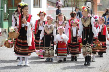Gara Bov, Bulgarya- 24 Nisan 2021: Kızlar saçlarını renkli ve zengin bir şekilde süslüyor ve köyde dolaşıp şarkılar söyleyip dans ediyorlar, bu şekilde evlenmeye hazır olduklarını gösteriyorlar.