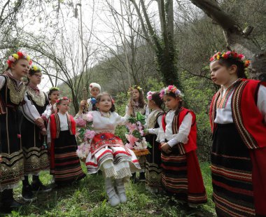 Gara Bov, Bulgarya- 24 Nisan 2021: Kızlar saçlarını renkli ve zengin bir şekilde süslüyor ve köyde dolaşıp şarkılar söyleyip dans ediyorlar, bu şekilde evlenmeye hazır olduklarını gösteriyorlar.