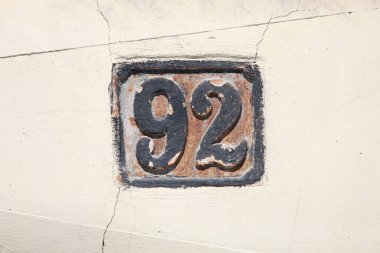 Eski model, kare, paslı, paslı bir plaka. Adres numarası da var. Yaklaş, marka..