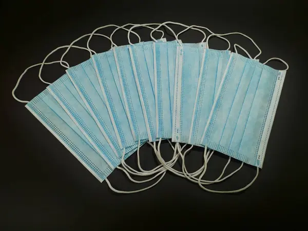 Koruyucu maskelerin görüntüsü pervane şeklinde koyu bir arkaplanda serili, virüslere karşı koruma