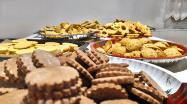 Noel kurabiyelerini yakın plan incelemeye hazır, arka planda diğer çerezler istiflenmiş, Noel için hazırlanıyorlar.