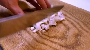 Küçük soğan parçalarını daha küçük parçalara ayıran yakın plan görüntüler, soğanları küçük parçalara ayıran bir bıçak tutan eller.