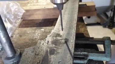 Çelik bir demir parçasını delen matkabın yavaş hareket eden ayrıntıları, metal talaşlı bir matkabın ayrıntıları, ev atölyesindeki bir matkap demiri deliyor.