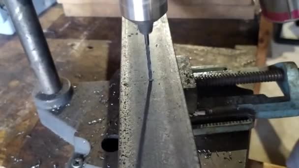 鉄の鋼片にドリルビットの遅い動きの詳細 金属削り出しのドリルの詳細 ホームワークショップでのドリルは 鉄の穴を作る — ストック動画