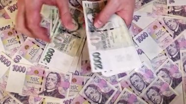 Arka planda iki bin Çek kronundan oluşan yığını sayan bir erkeğin yakın plan görüntüsü, gevşek aralıklarla 1000 kron banknot, yavaş çekim, para 