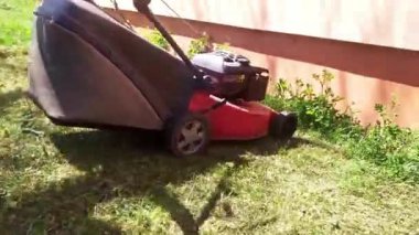 Bahçedeki çimleri biçen bir adamın aile evinin etrafındaki çim biçme makinesi manzarası, güzel güneşli bir gün.
